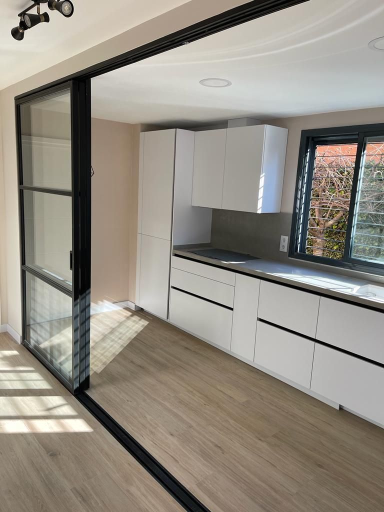 Una cocina con gabinetes blancos y puertas corredizas de vidrio.