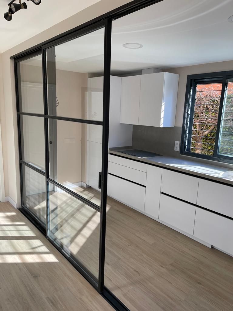 Una cocina con gabinetes blancos y puertas corredizas de vidrio.