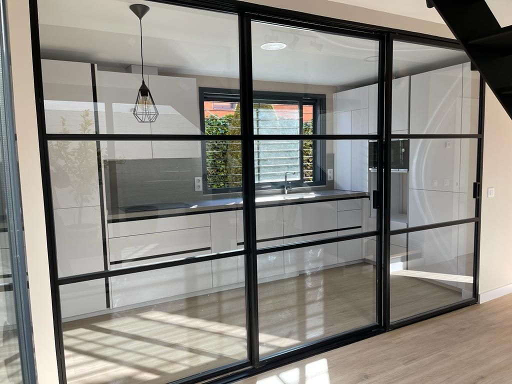 Una cocina con una puerta corrediza de vidrio entre la cocina y la sala de estar.