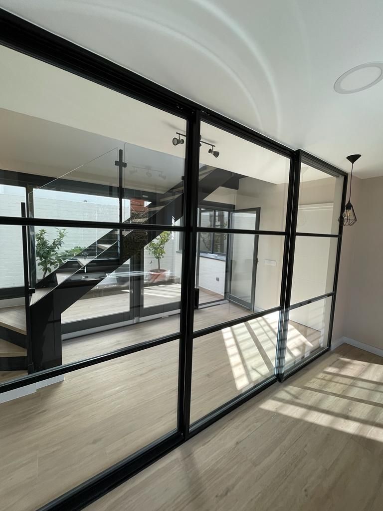 Una habitación con una escalera detrás de una pared de cristal.