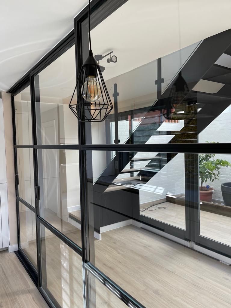 Una habitación con una escalera detrás de una pared de cristal y una luz colgando del techo.