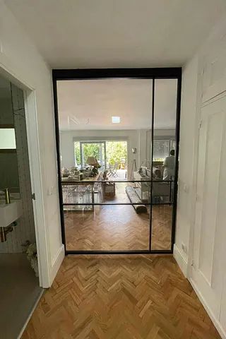 Un pasillo con una puerta de cristal que conduce a una sala de estar.
