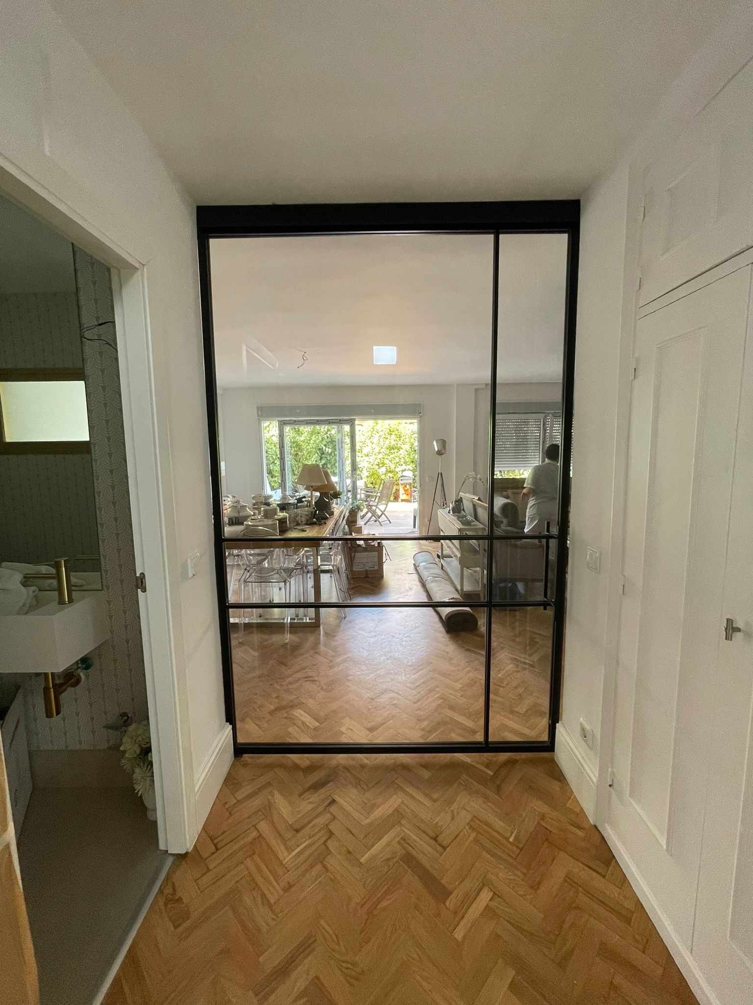 Un pasillo con una puerta corrediza de vidrio que conduce a una sala de estar.