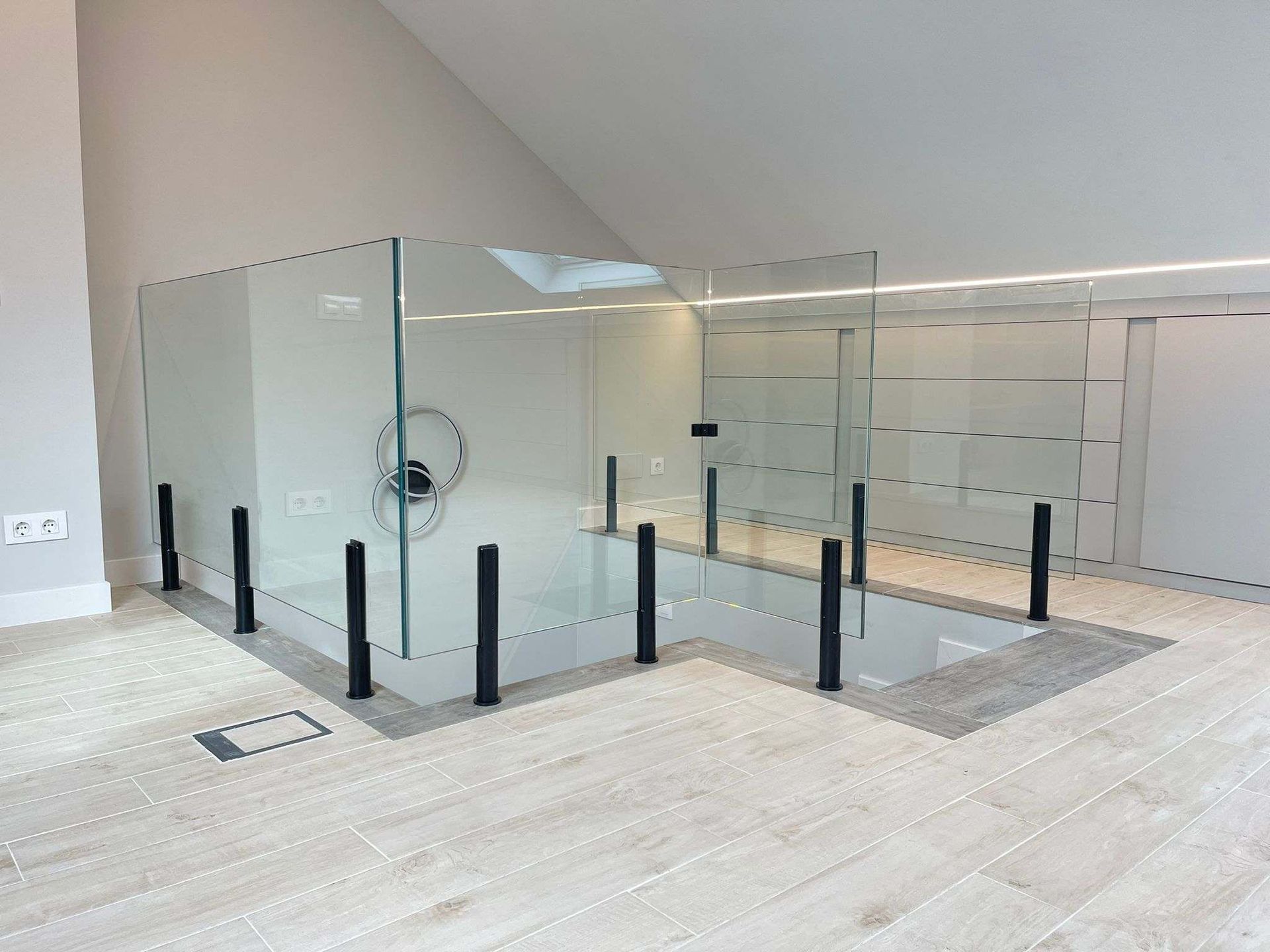 Una habitación vacía con una barandilla de cristal y una escalera.