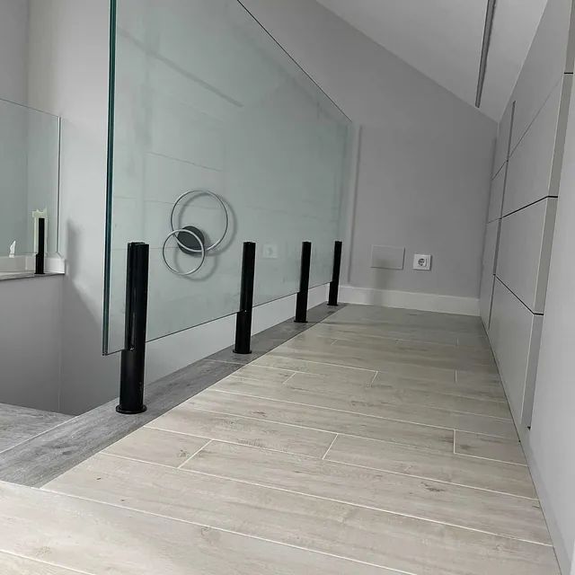 Un pasillo con barandilla de cristal y suelo de madera.