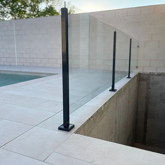 Una piscina con una barandilla de cristal que la rodea.