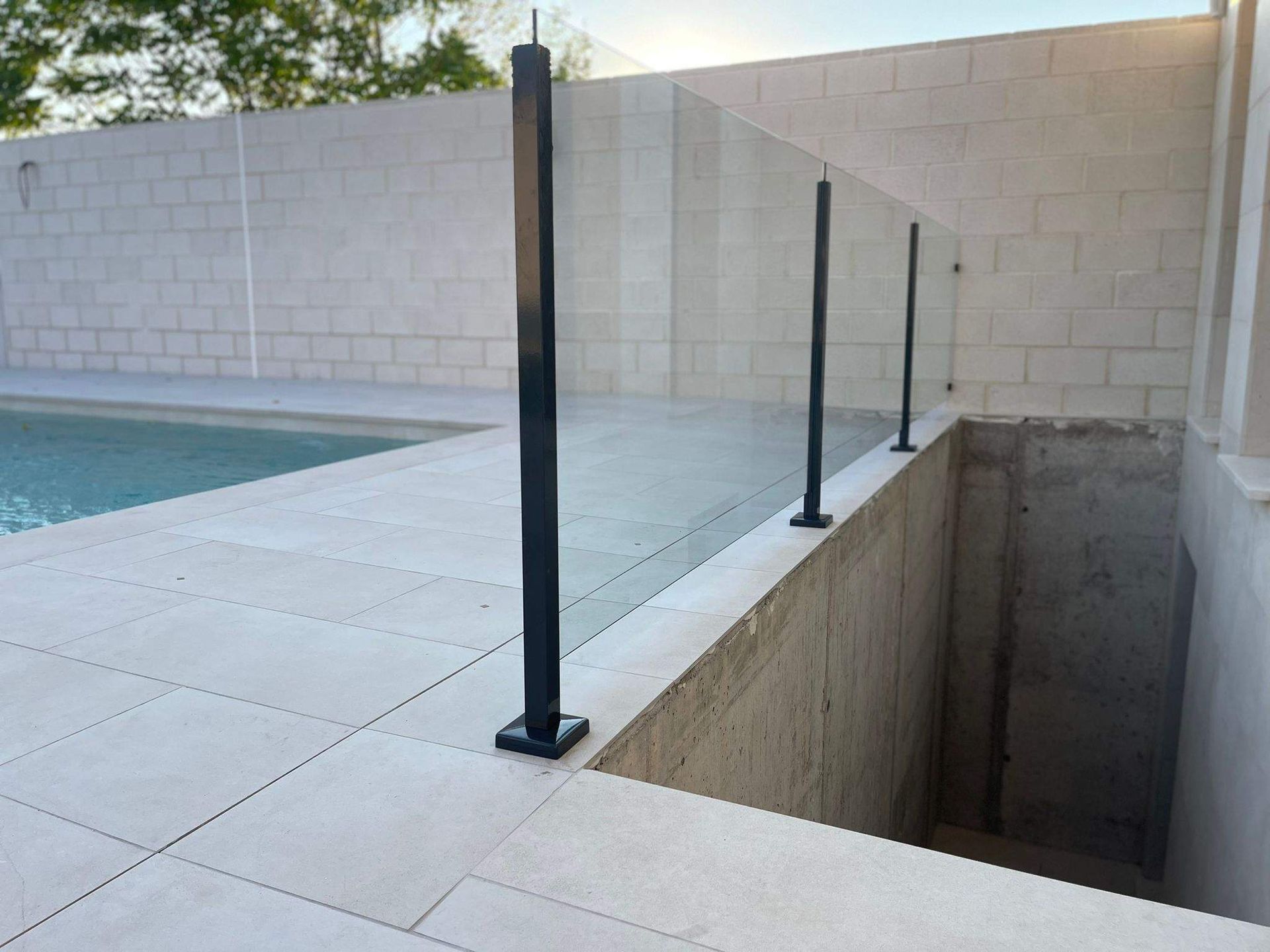 Una piscina con barandilla de cristal y escaleras que conducen a ella.