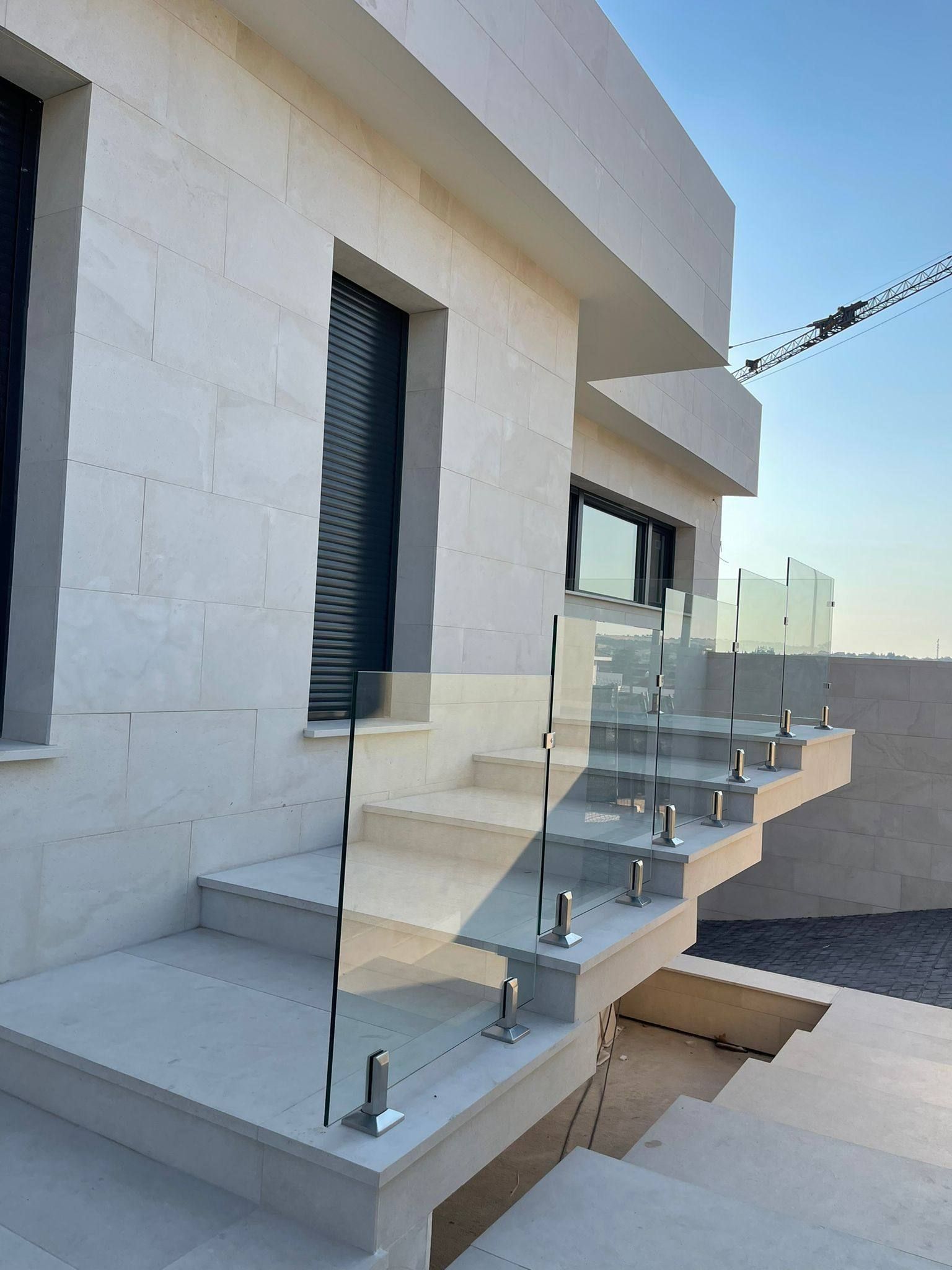 Un conjunto de escaleras con barandilla de vidrio en el costado de un edificio.