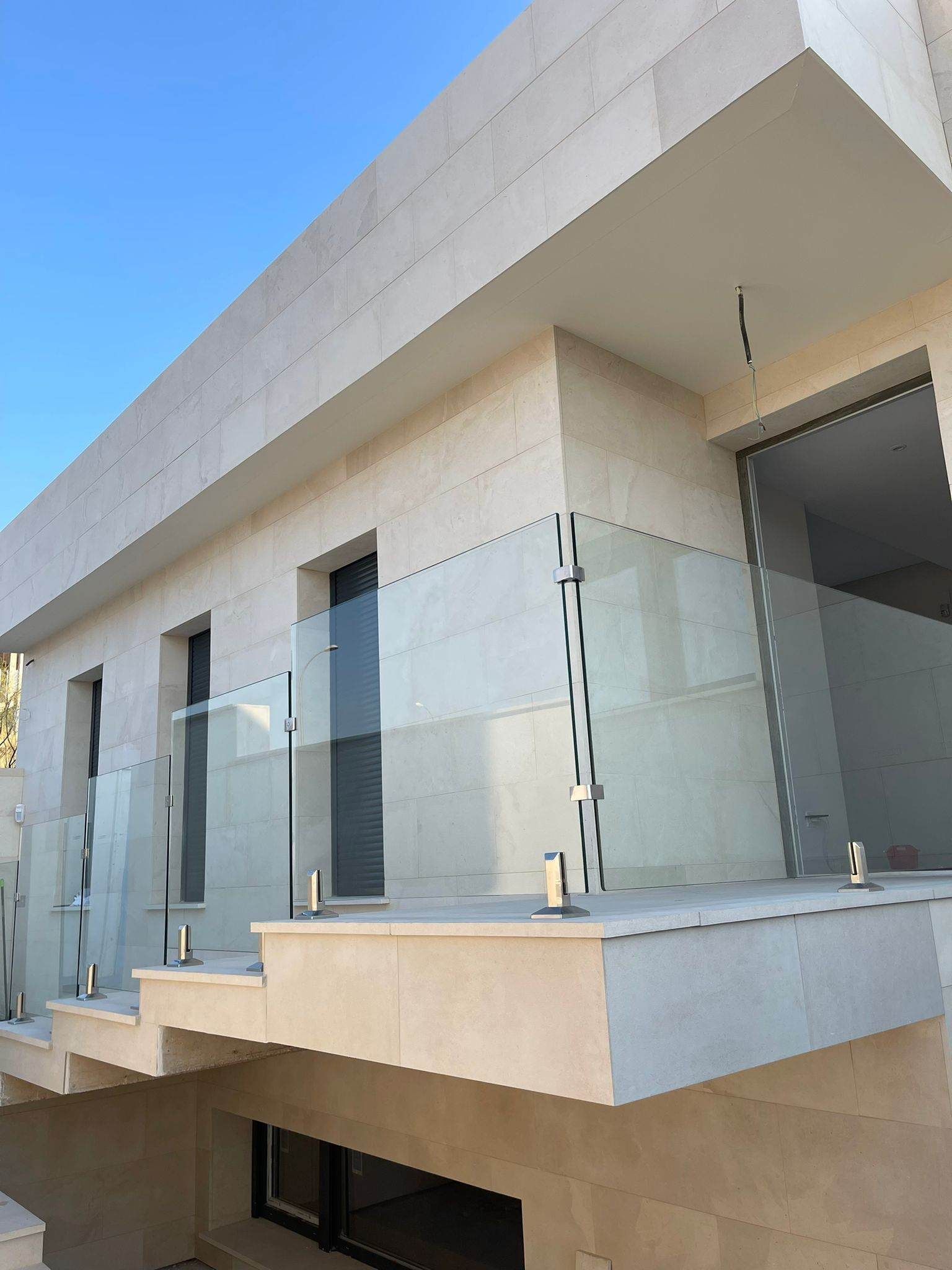 Un balcón con barandilla de vidrio en el costado de un edificio.