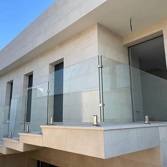 Un balcón con barandilla de vidrio en el costado de un edificio.