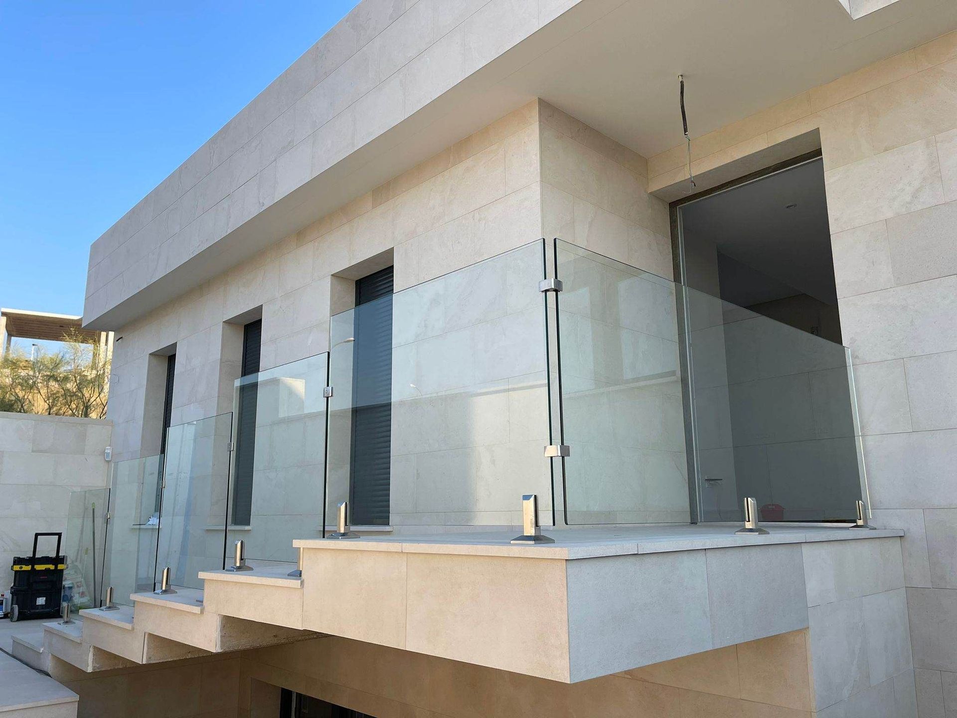 Un balcón con barandilla de vidrio en el costado de un edificio.