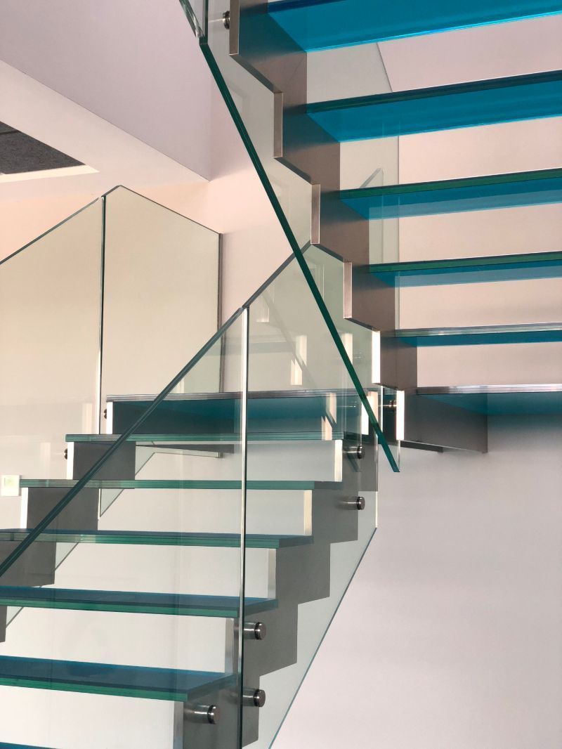 Una escalera con escalones azules y una barandilla de cristal.