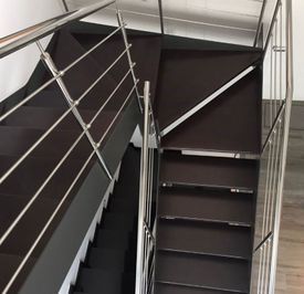 Una escalera con barandilla de acero inoxidable y escalones de madera.