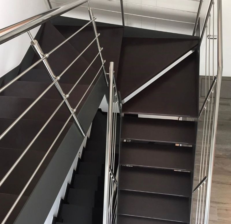 Una escalera con barandilla de acero inoxidable y escalones de madera.