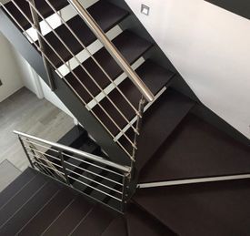 Una escalera con barandilla de acero inoxidable y escalones de madera.