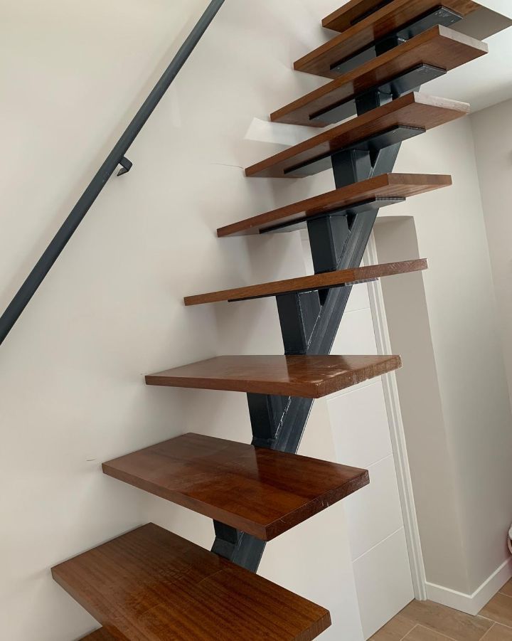 Una escalera de madera con barandilla de metal en una habitación.