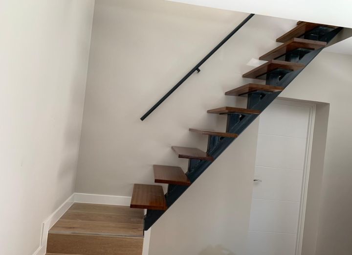 Una escalera con escalones de madera y barandilla de metal