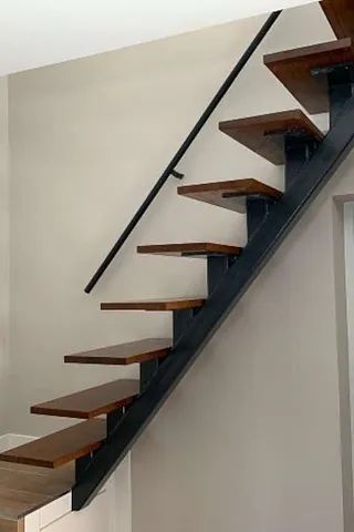 Una escalera con escalones de madera y barandilla de metal en una habitación.