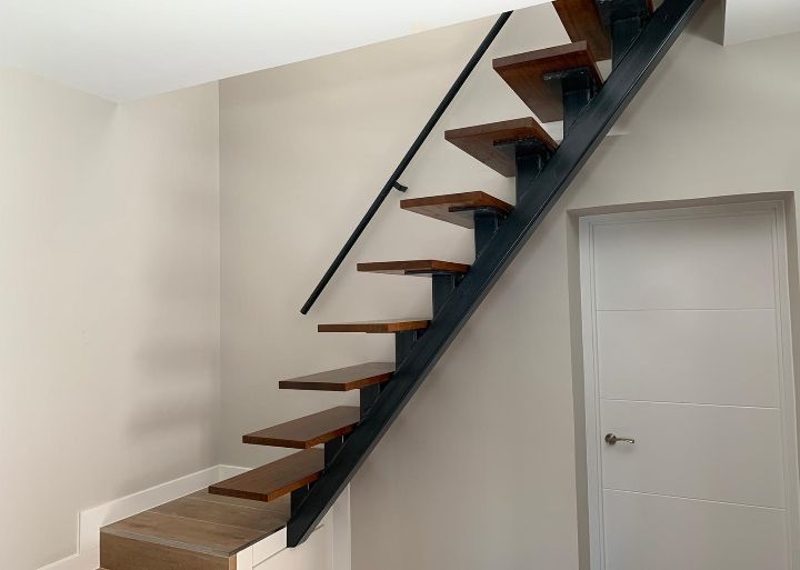 Una escalera con escalones de madera y barandilla de metal en una habitación.