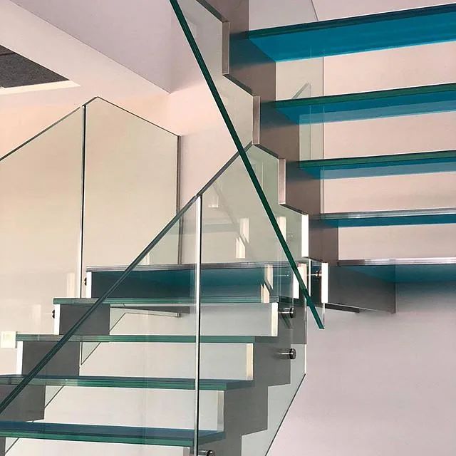 Una escalera con escalones azules y una barandilla de cristal.