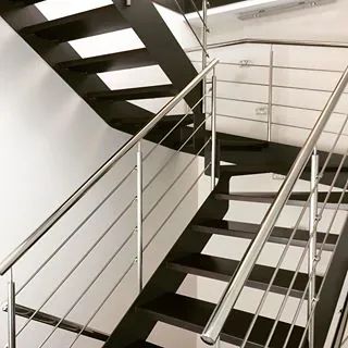 Una escalera en blanco y negro con barandilla de acero inoxidable.