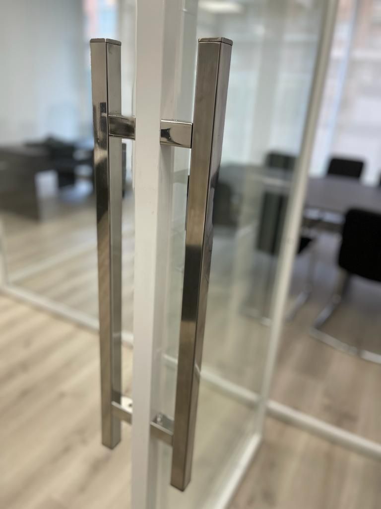 Un primer plano de una manija de puerta de acero inoxidable en una puerta de vidrio.