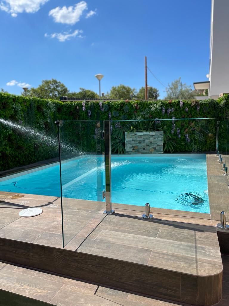 Una gran piscina con una valla de cristal a su alrededor.