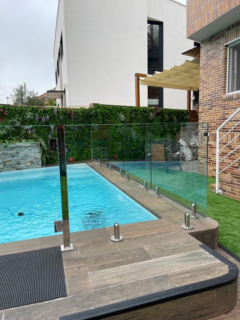 Una gran piscina con una valla de cristal a su alrededor.