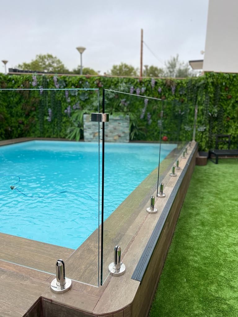 Una piscina con una valla de cristal a su alrededor.