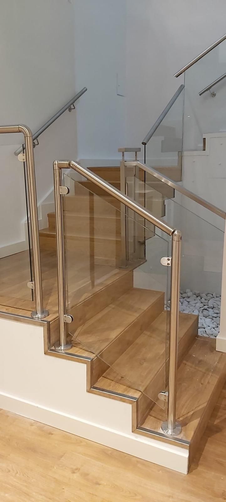 Una escalera con escalones de madera y barandilla de cristal.