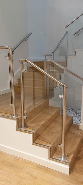 Una escalera con escalones de madera y barandilla de cristal.