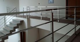 Una escalera con barandilla de acero inoxidable y un reloj en la pared.