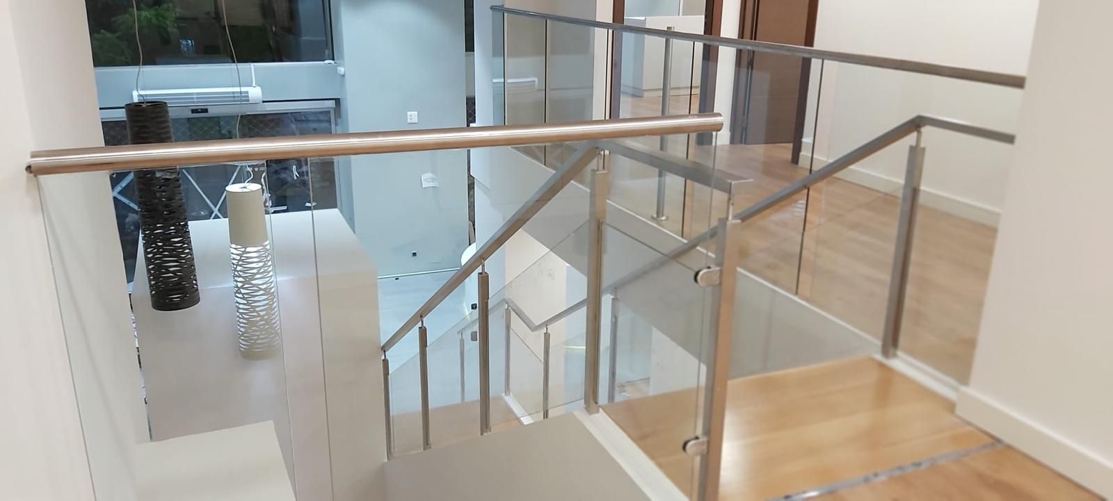 Una escalera con barandilla de cristal y barandilla de acero inoxidable.