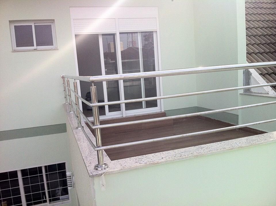 Un balcón con barandilla de acero inoxidable y suelo de madera.