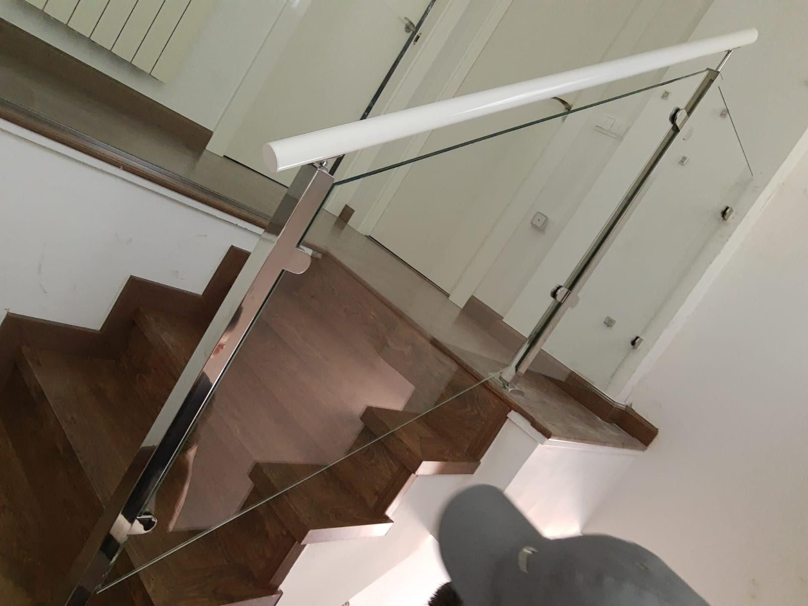 Una escalera con barandilla de cristal y escalones de madera.