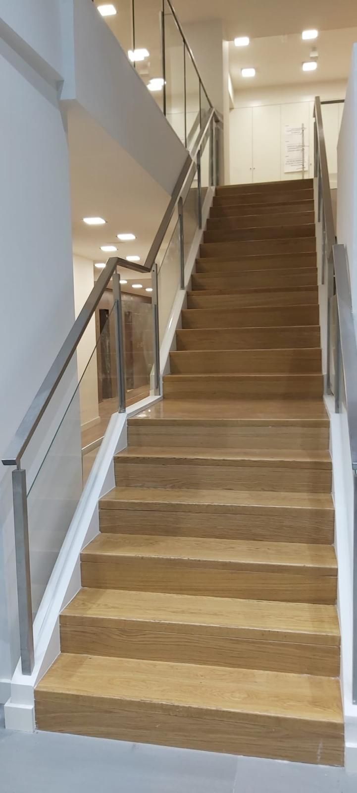 Un conjunto de escaleras de madera con barandilla de vidrio en un edificio.