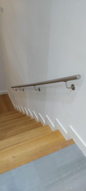 Una escalera con escalones de madera y pasamanos de acero inoxidable.