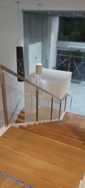Una escalera con escalones de madera y barandilla de cristal.