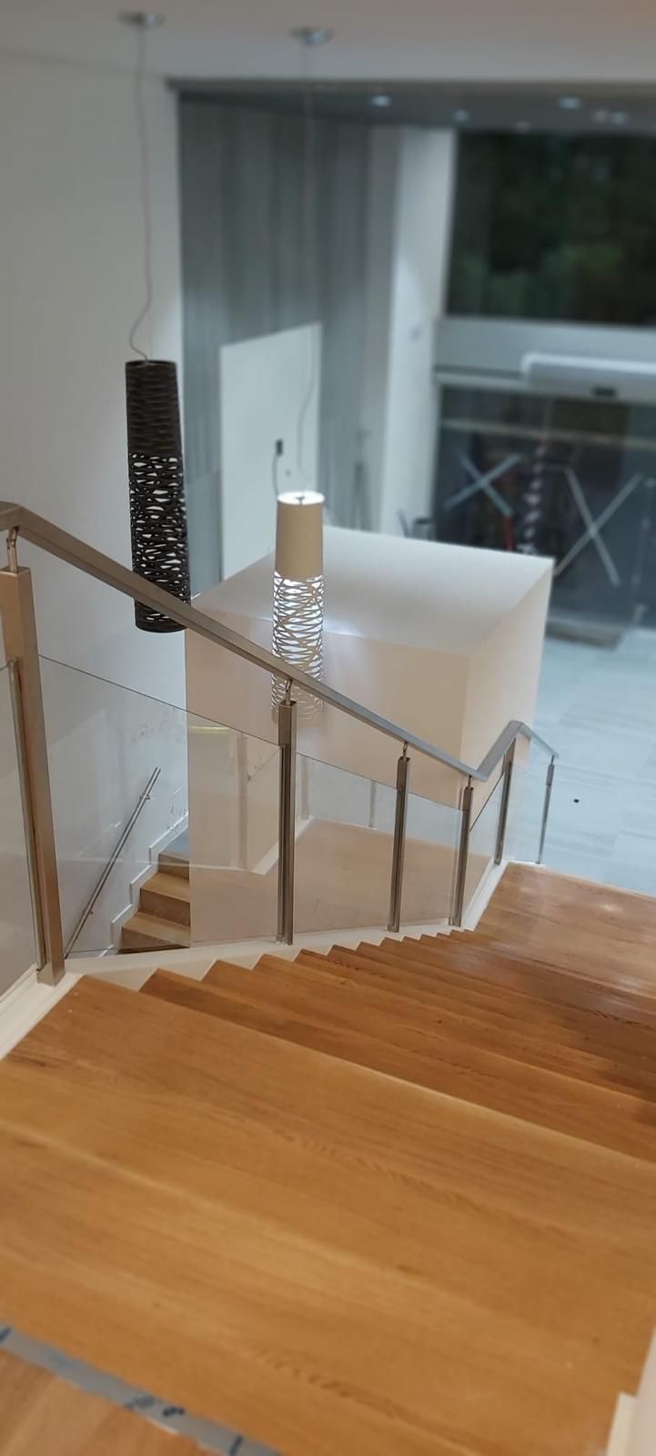 Una escalera con barandilla de cristal y barandilla de acero inoxidable.