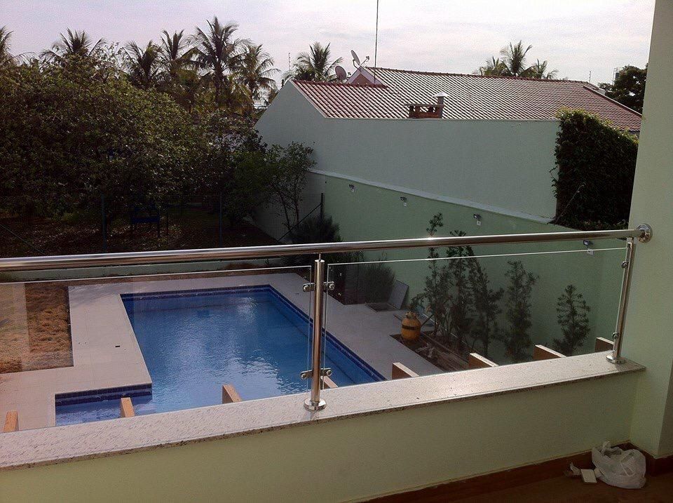 Un balcón con vistas a una piscina con barandilla de acero inoxidable.