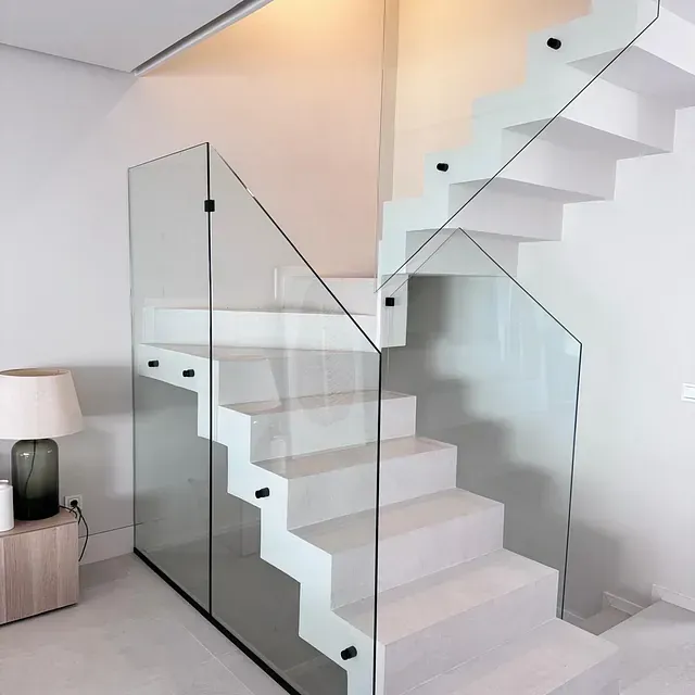 Una escalera blanca con barandilla de cristal en una habitación.