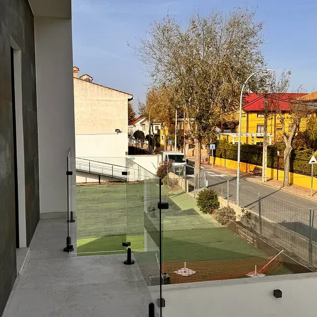 Una vista de una ciudad desde un balcón con barandilla de cristal.