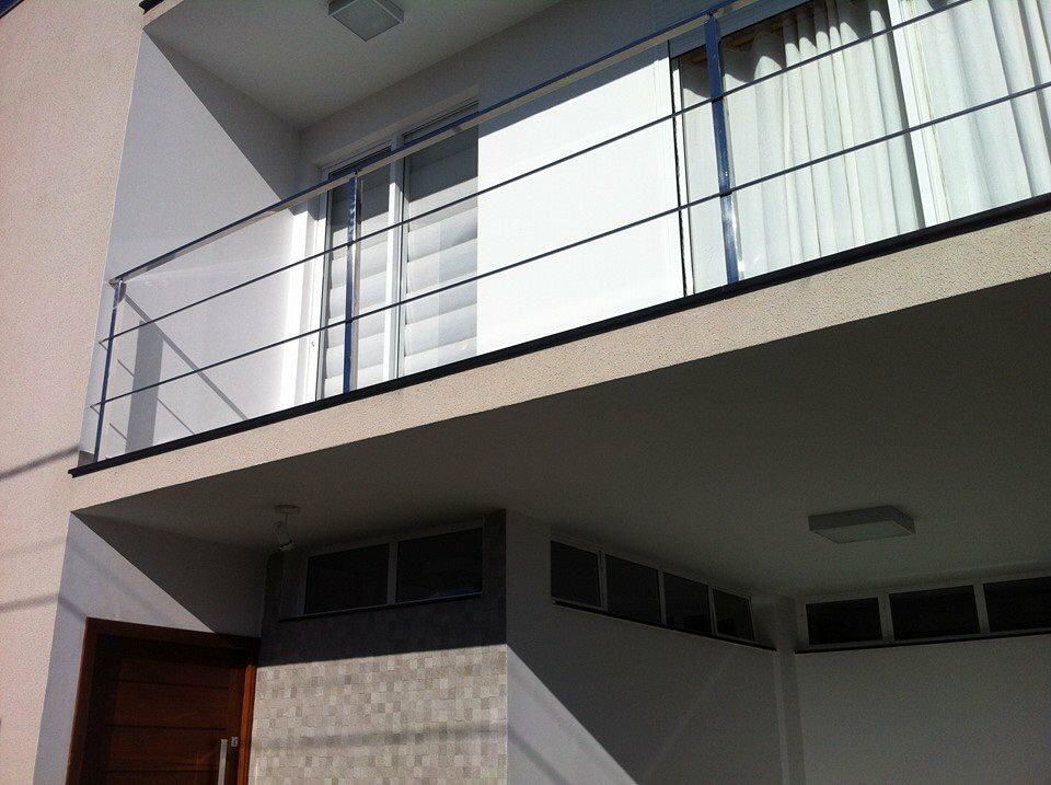 Un balcón con barandilla de acero inoxidable y cortinas blancas.