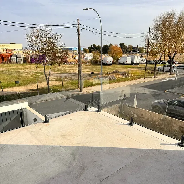 Una vista de una calle desde un balcón con barandilla de vidrio.