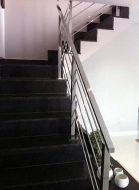 Un conjunto de escaleras negras con barandilla de metal.