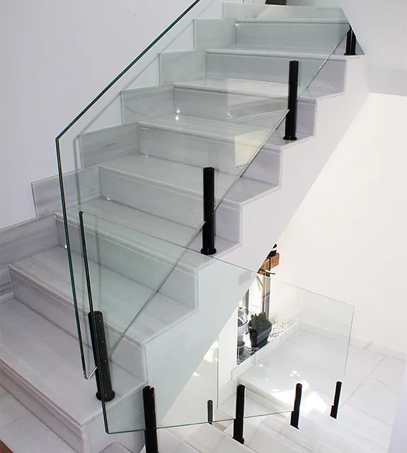 Una escalera blanca con una barandilla de vidrio transparente.