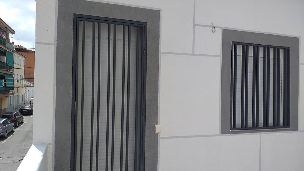 Un edificio blanco con una puerta negra y dos ventanas.