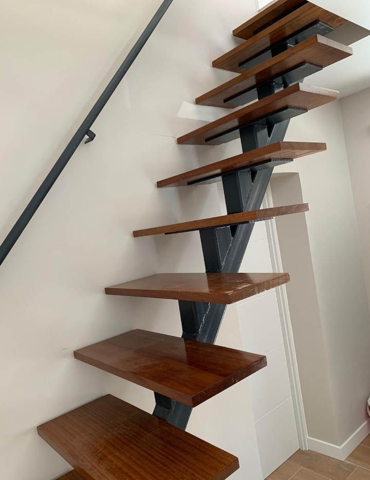 Una escalera de madera con barandilla de metal en una habitación.