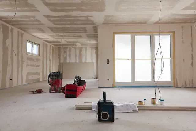 Una habitación vacía en construcción con una aspiradora y herramientas en el suelo.