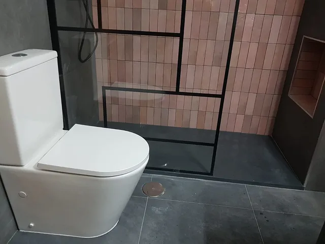 Un baño con inodoro y ducha a ras de suelo.